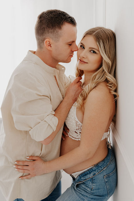 Babybauchfoto einer schwangeren Frau im Studio mit Stricktop und Schleierkraut in der Hand – natürliches Schwangerschaftsshooting im Fotostudio in Leipzig