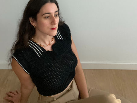 Woman wearing a black crochet polo shirt with white details on the collar and sleeves.