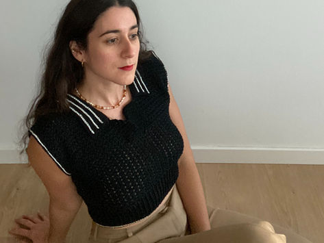 Woman wearing a black crochet polo shirt with white details on the collar and sleeves.