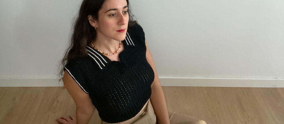 Woman wearing a black crochet polo shirt with white details on the collar and sleeves.