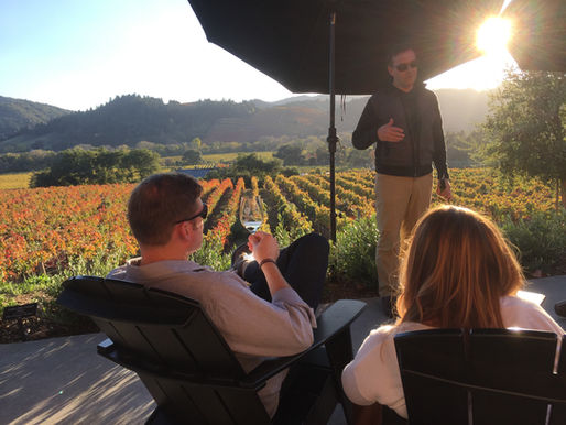 A couple enjoys a serene wine tasting experience in Napa, taking in the picturesque vineyard views under the warm glow of the setting sun.