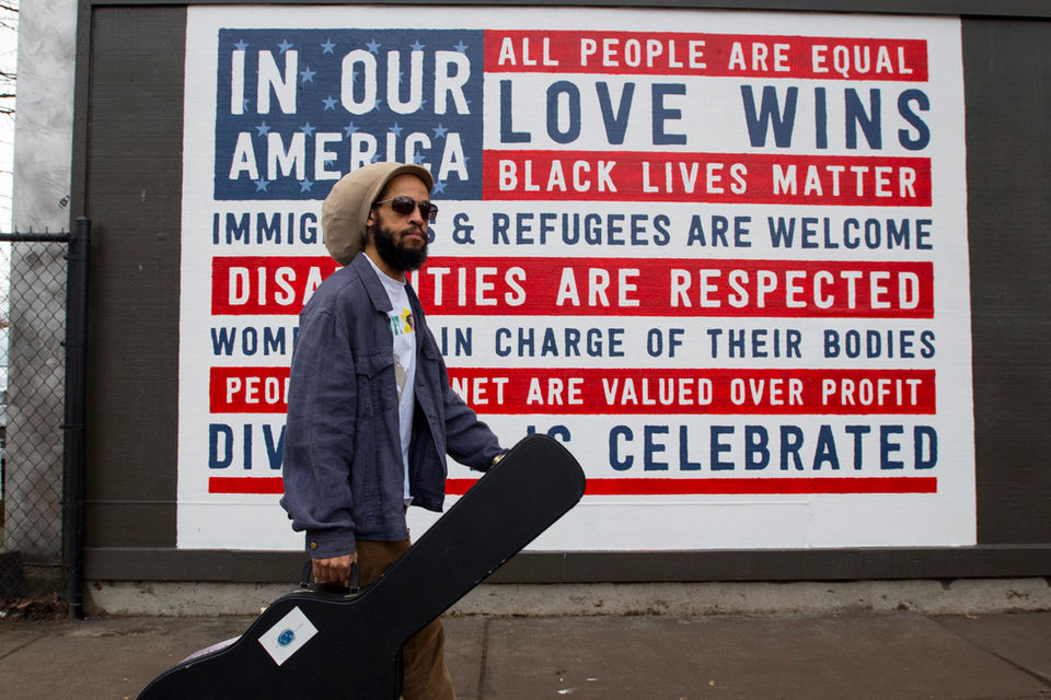 Mural Nigel walking in front of an In Our America Sign