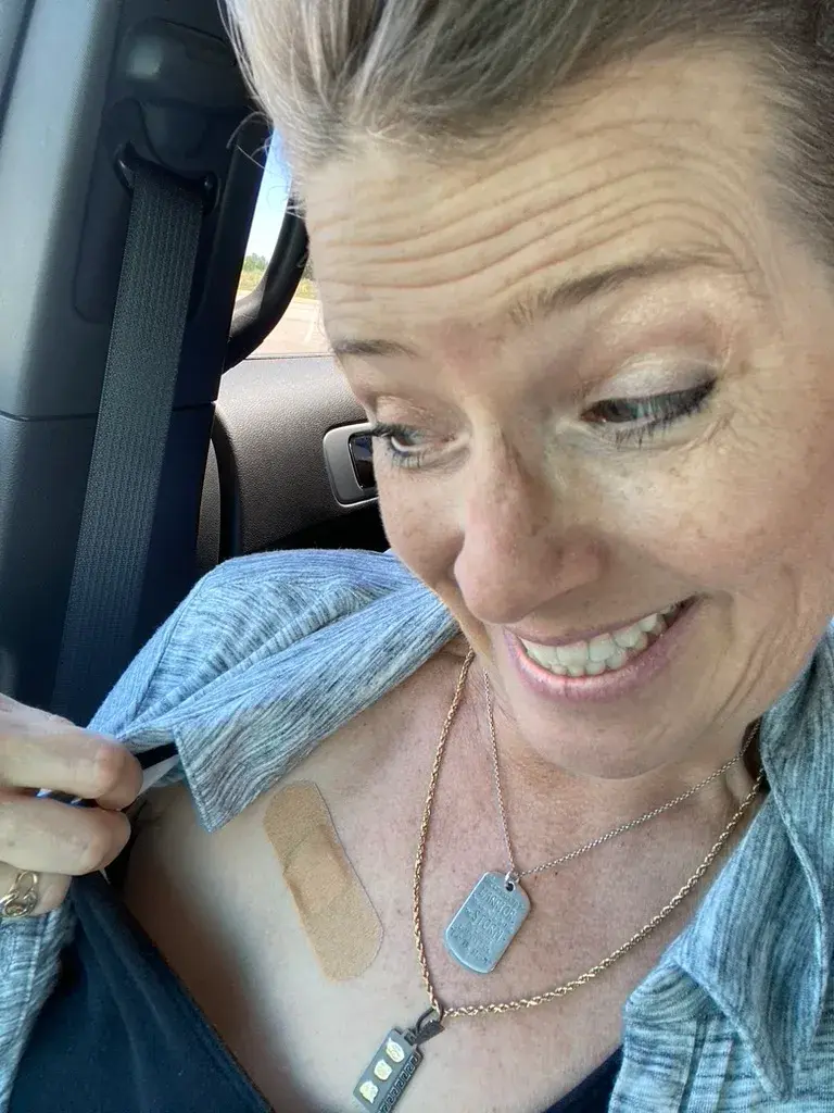 CC with her gray shirt open showing off a bandaid covering her new port removal scar!