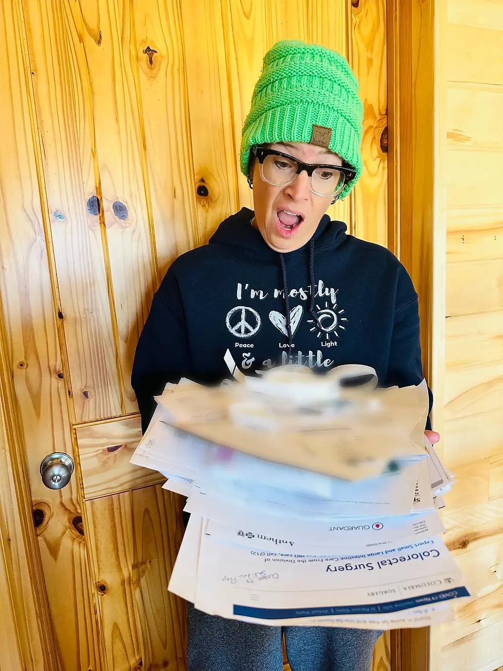 CC in a blue hoodie and green hat holds a pile of paperwork from cancer treatment. Her look says: “Can you believe this?