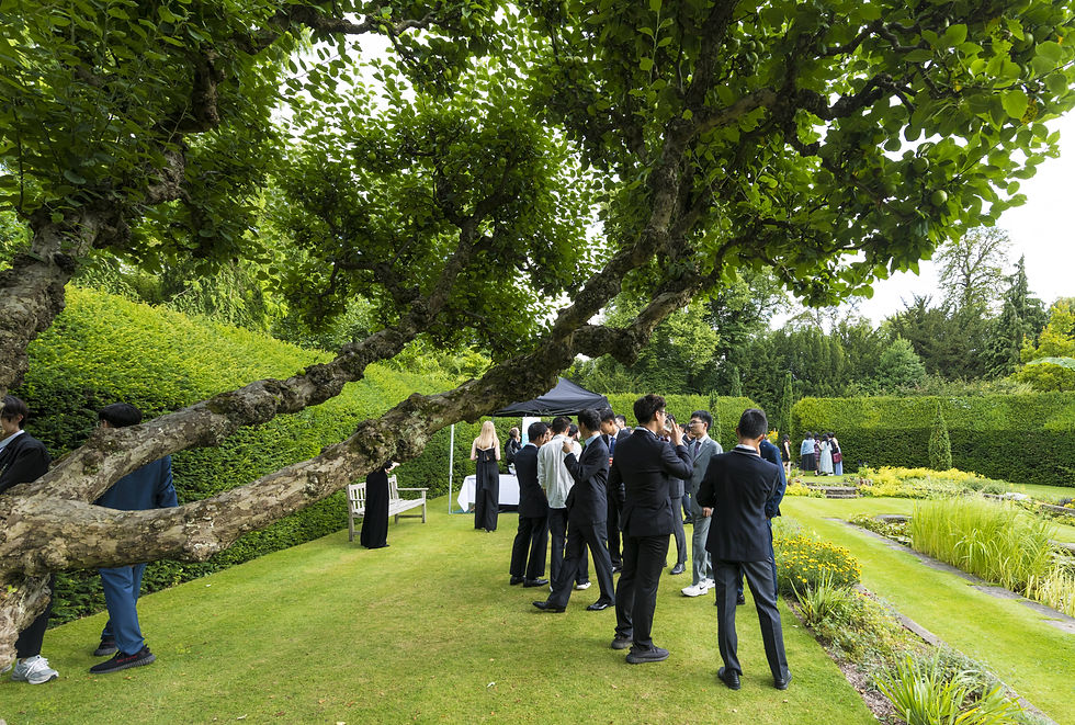 Teenagers gathered in a University College garden for a formal event