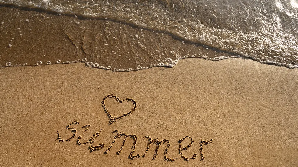 le mot Summer écrit à la main dans le sable avec un coeur au dessus du mot