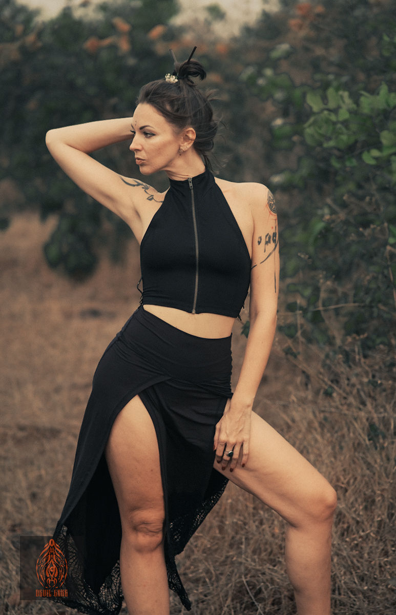 Thumbnail: Woman wearing black SIAMESE Cotton Halter Zip Top with Lace Up Back, high slit skirt outdoors.