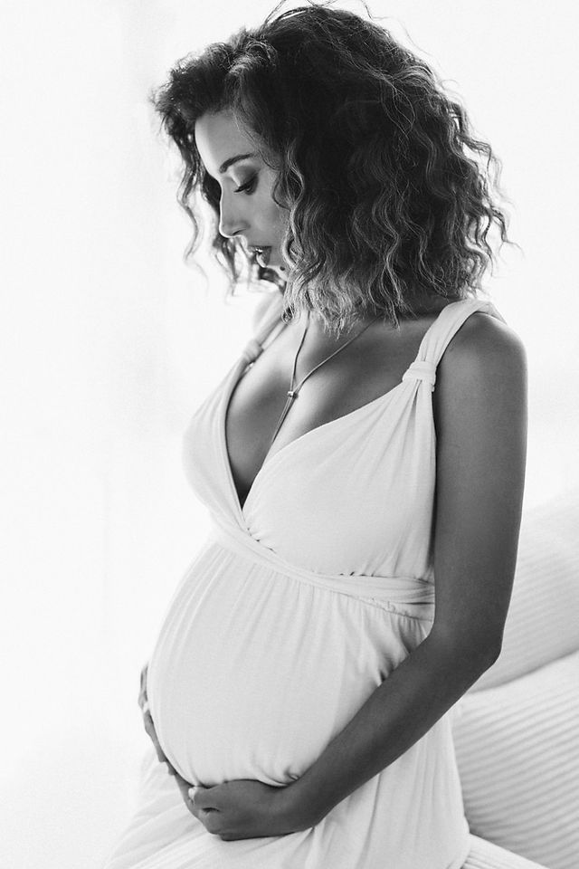 Pregnant woman in flowing white maternity dress at NYC photography studio