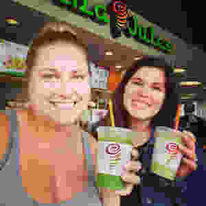 Two grirls smiling with green smoothies at Jamba Juice.