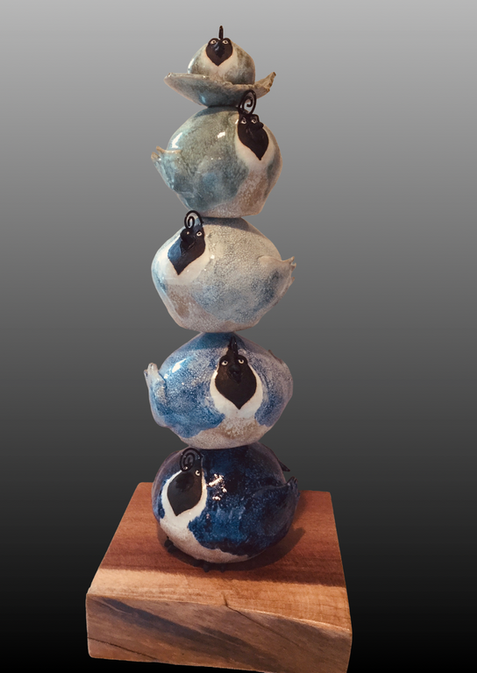Totem sculpture of stacked blue pottery, on wood base.
