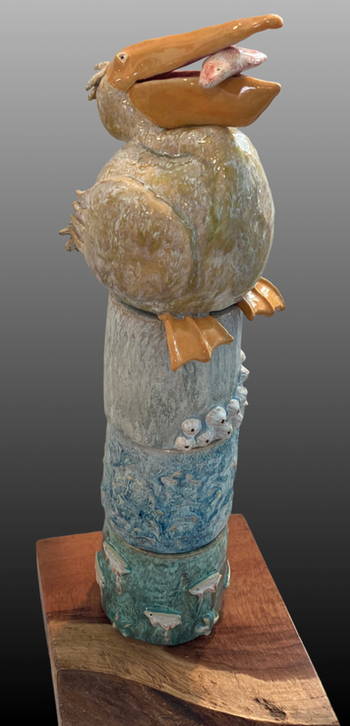 Ceramic pelican sculpture with fish in beak, stacked blue and white totem pottery.
