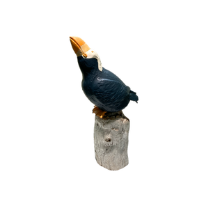 Ceramic puffin sculpture on a stump, dark blue and white.