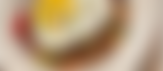 A colorful bowl of seasoned rice mixed with sliced kielbasa, mushrooms, carrots, sweet peas, and red peppers, topped with a sunny-side-up egg and garnished with scallions. A vibrant, Tampa Bay–inspired twist on classic Caribbean rice and eggs.