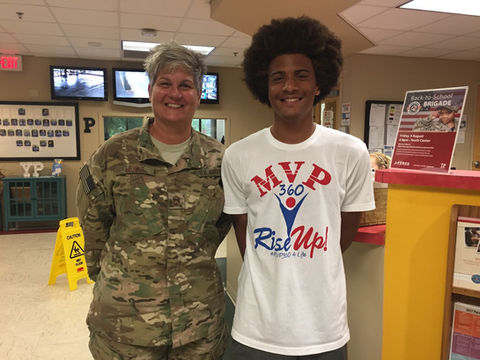 Soldier with teen poses near Rise Up! MVP360 Sports youth development program.