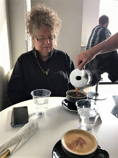 woman seated at table having coffee poured for her