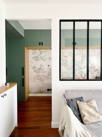 Vue du coin chambre depuis le salon, ajout d'une cloison partielle avec entrée sur le coin chambre d'une part et entrée sur le coin bureau d'autre part. Au centre une verrière pour laisser la lumière et ne pas réduire l'espace. Pont de placards dans un vert GreenSmoke de chez Farrow and ball et habillage bois massif en chêne, papier peint Kam & Léon "Arbre du lac". un mélange de contemporain et d'influences asiatiques chers aux clients.