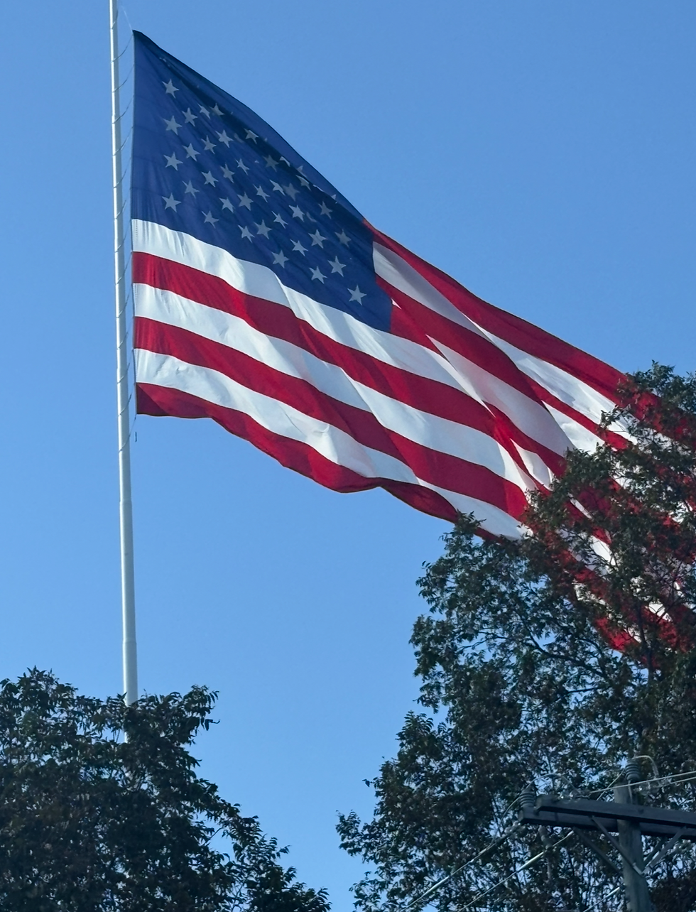 American flag waving in the blue sky, symbolizing faith, freedom, and purpose