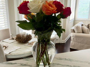 Pink roses with a sign that reads ‘begin each day with a grateful heart’ on a kitchen counter