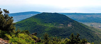 Veduta panoramica del Monte Gibele a Pantelleria, cratere vulcanico ricoperto di vegetazione, al centro di un’indagine sulle origini sacre del nome.