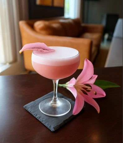 pink cocktail on black napkin with pink flower