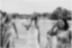 A bride and her friends walk along a Buffalo lakeshore laughing.