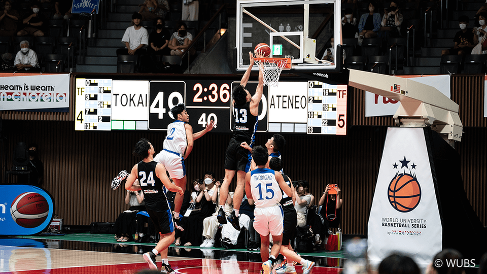 A basketball player in a black jersey jumps for a layup during the World University Basketball Series. 