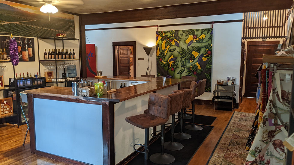 A three-sided wood bar stands in the room, surrounded by art work and racks of wine.