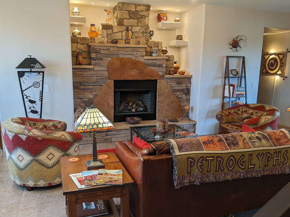 Cozy Southwestern ambience of Origins B&B's Great Room, with a stone fireplace, patterned chairs, leather sofa, and a PETROGLYPHS blanket.