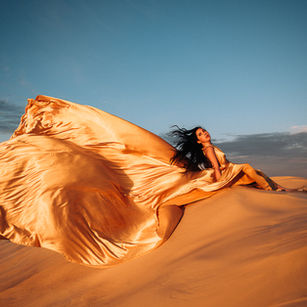 Girl in fold flying dress on sand dunes