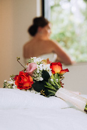 bride looking out window with flower in foreground