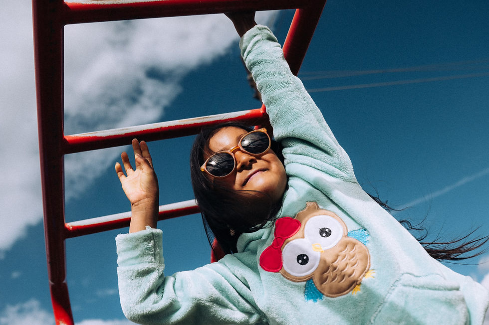 child in ecaudor swinging on monkey bars in cute sweater and sunglasses