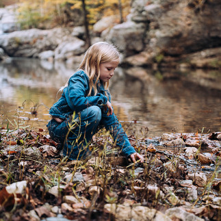tween girl picking up leaves in a creek