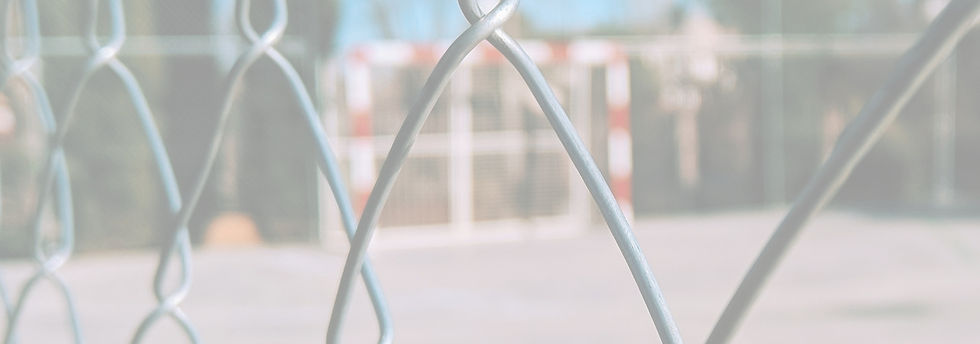 up close image of a chain link fence, looking into a schoolyard. 