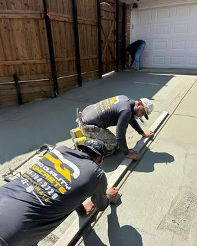 The Pro Quality team uses precision tools to cut straight control joints into a newly poured residential driveway in Wylie, TX.