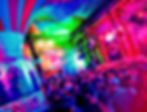 A packed nightclub with colorful neon lights, artistic graffiti, and people enjoying a lively atmosphere on the dance floor.