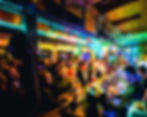 A bustling ruin bar in Budapest with patrons gathered around the bar, vibrant lighting, and a cozy wooden interior creating a lively social atmosphere.
