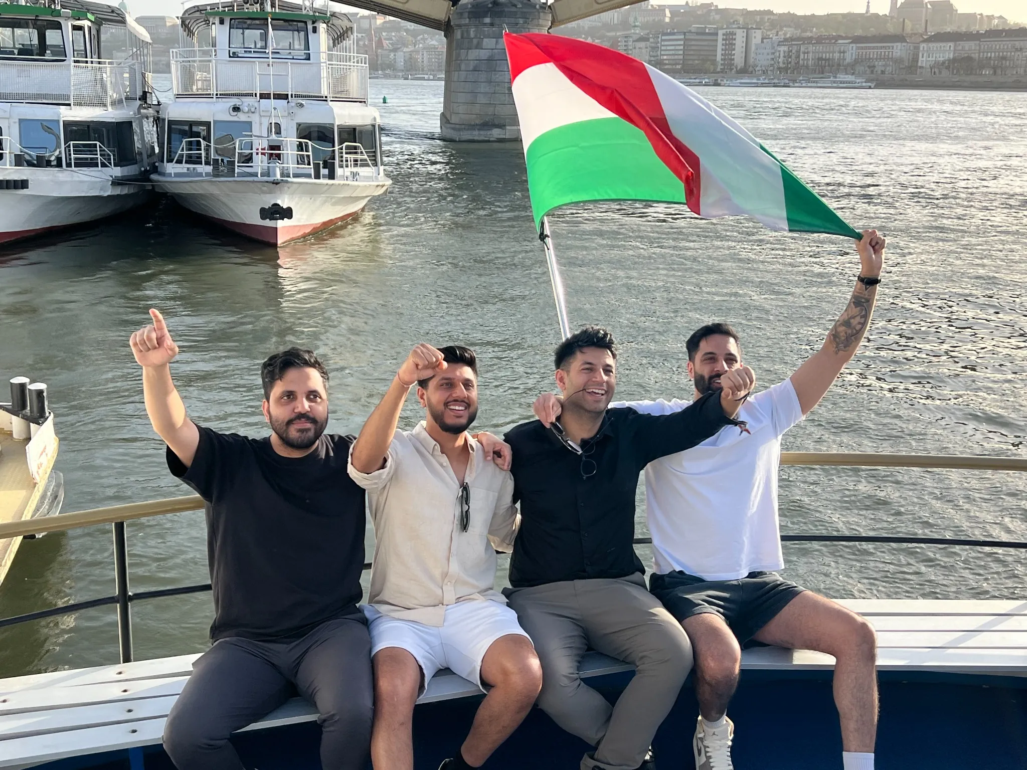 Private boat cruise Budapest stag group posing on deck with a Hungarian flag on the Danube River.