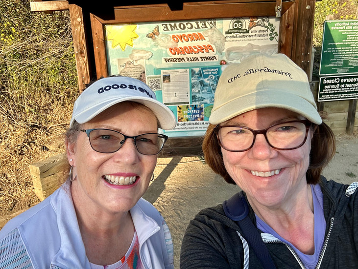 Two women smile at the start of a hike.