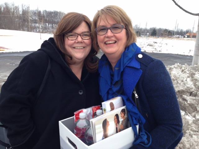 A woman accepting a gift box from a female friend.