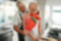 Man surprises his wife with roses while she is preparing a meal.