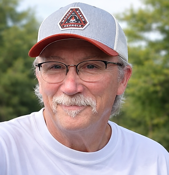 Smiling man wearing glasses and a gray, red, and white hat.