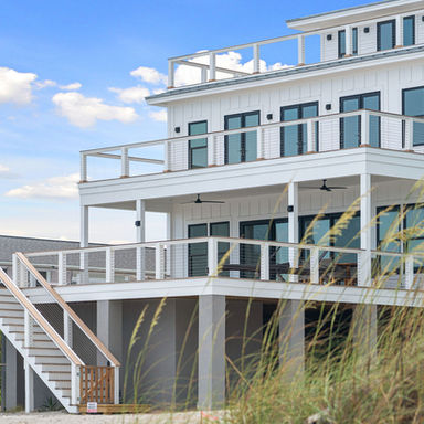 Folly Beach oceanfront home in board-and-batten with stacked cable-rail decks on a concrete pile foundation