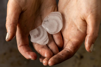 Halves of a hailstone are held in two palms.