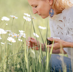 Es zeigt eine Blumenwiese mit einer dame die an der blume riecht.