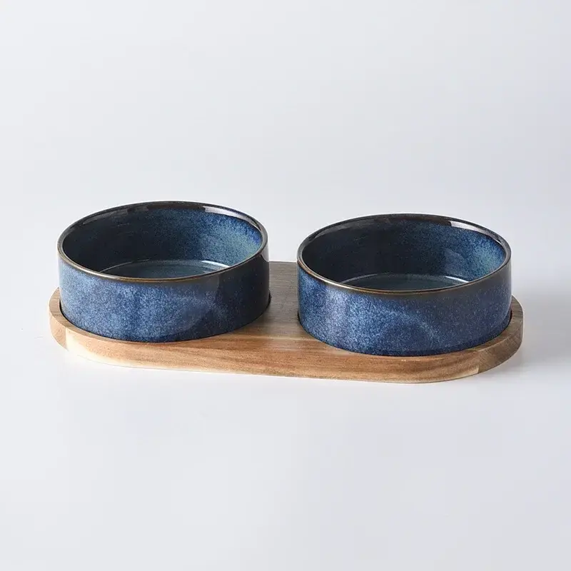Two blue ceramic cat food bowls on a wooden stand
