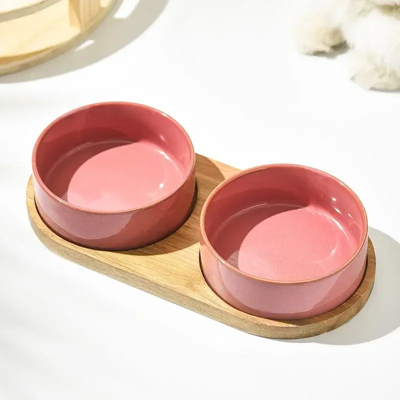 Thumbnail: Pink ceramic pet food and water bowls on a wooden stand