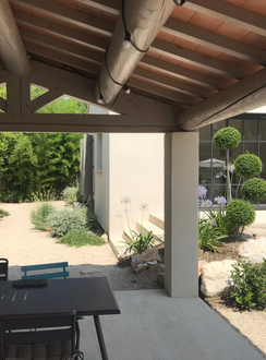 belle terrasse ombragée sous un toit de tuiles traditionnelles provençales. cet auvent permet de déguster un bon repas entre amis avant d'aller plonger dans la piscine. Grâce au beau jardin provençal, il s'intègre parfaitement dans la nature