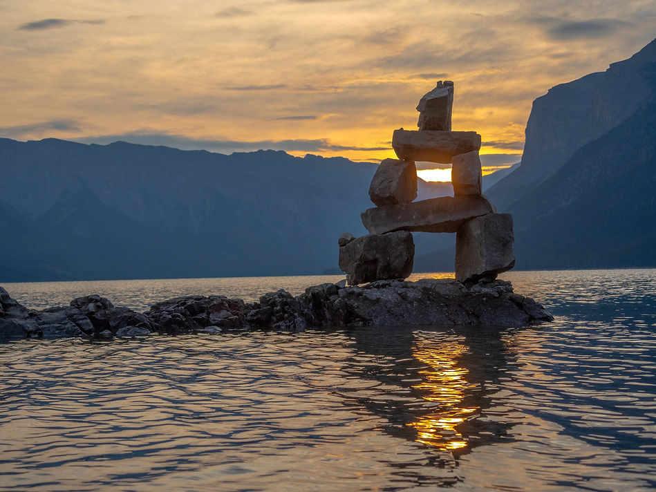 Canadian Inuit stone figure inukshuk in lake with mountains totem.jpg