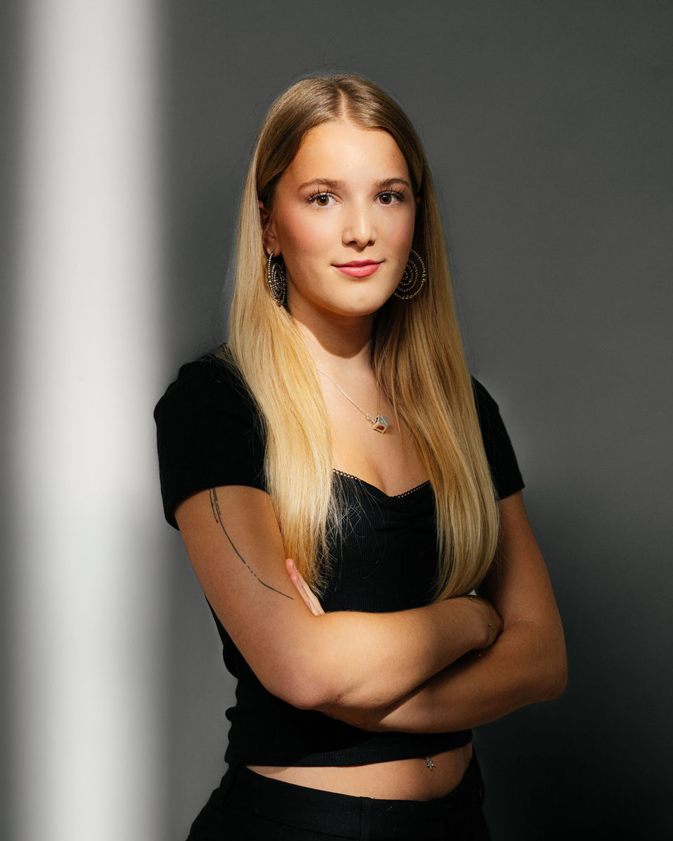 Portraitbild von Enya Sägesser in schwarzer Kleidung, Lichtschein im Hintergrund