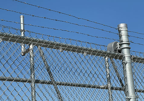 Close up of barb wire topper on chainlink security fence